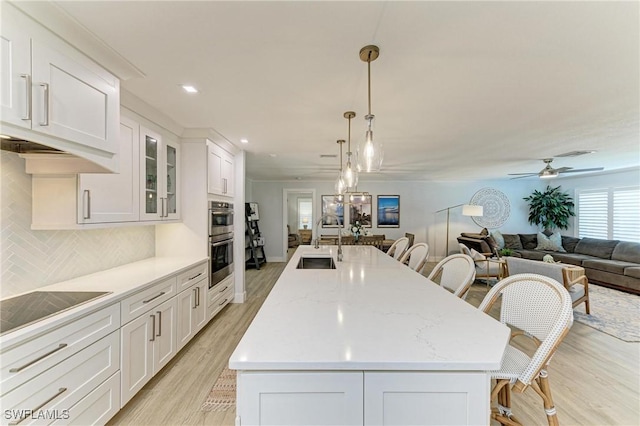 621 Trabue Ave, Punta Gorda, FL 33950 - kitchen with a sink, a kitchen breakfast bar, stainless steel double oven, black electric stovetop, and a kitchen island with sink