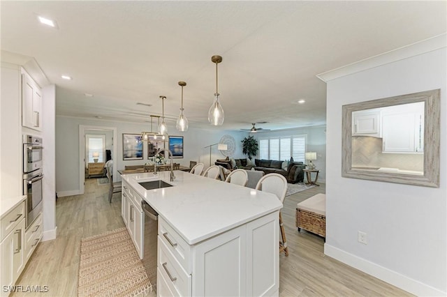 621 Trabue Ave, Punta Gorda, FL 33950 - kitchen featuring white cabinets, a breakfast bar, stainless steel appliances, an island with sink, and a sink