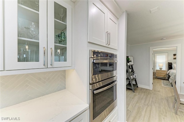 621 Trabue Ave, Punta Gorda, FL 33950 - kitchen featuring light wood-type flooring, double oven, white cabinets, light stone countertops, and glass insert cabinets