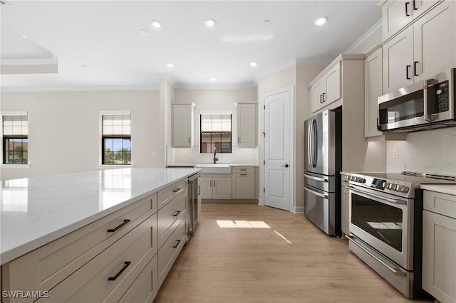 kitchen featuring crown molding, stainless steel appliances, recessed lighting, a sink, and light wood-type flooring