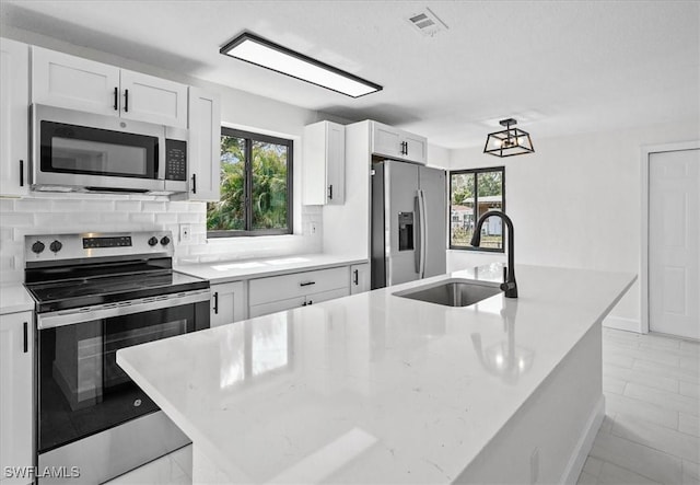 3652 Hibiscus Ave, Naples, FL 34104 - kitchen with visible vents, a sink, backsplash, white cabinetry, and appliances with stainless steel finishes