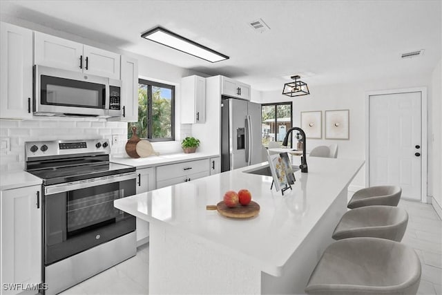 3652 Hibiscus Ave, Naples, FL 34104 - kitchen with tasteful backsplash, visible vents, appliances with stainless steel finishes, white cabinetry, and a sink