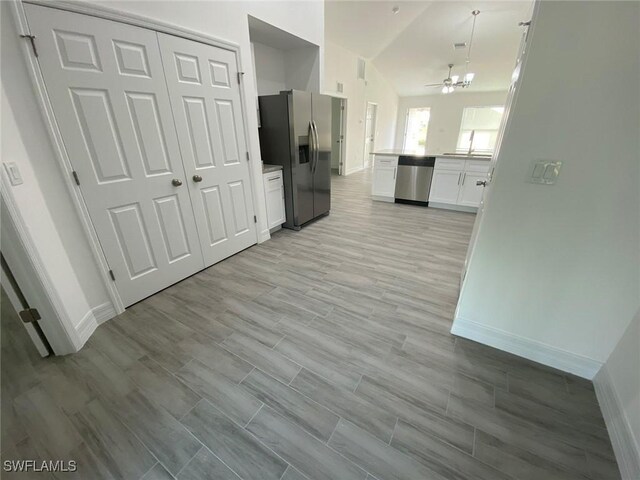 kitchen with wood tiled floor, light countertops, lofted ceiling, stainless steel appliances, and white cabinetry