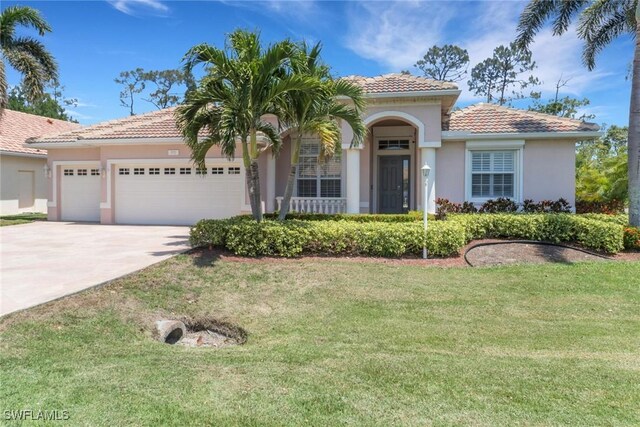 24840 Divot Dr, Bonita Springs, FL 34135 - mediterranean / spanish-style house with a garage, concrete driveway, stucco siding, a tiled roof, and a front lawn
