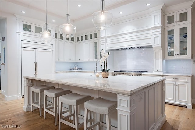 kitchen with white cabinetry, tasteful backsplash, light wood-style flooring, and a sink