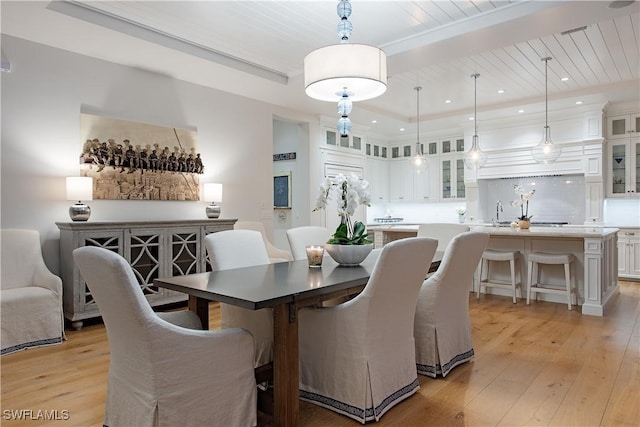 dining room featuring recessed lighting, a raised ceiling, and light wood-style floors