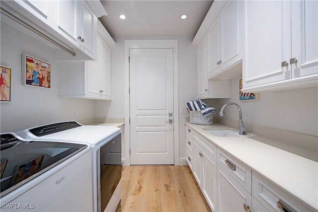 washroom featuring recessed lighting, separate washer and dryer, cabinet space, a sink, and light wood-type flooring