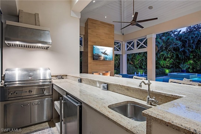 kitchen with light stone counters, fridge, and a sink