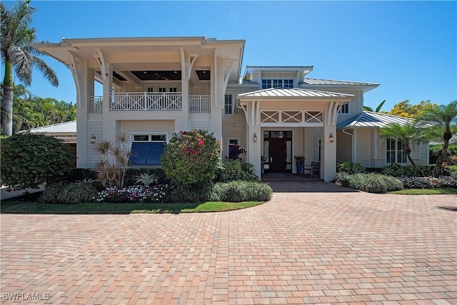 view of front of house featuring a standing seam roof and a balcony