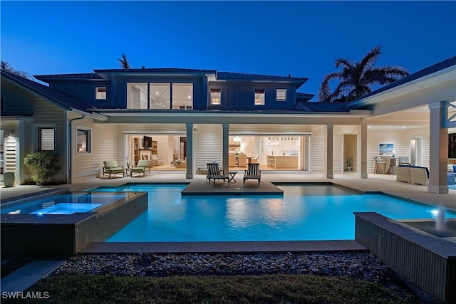 back of property with an outdoor pool, a patio area, and an in ground hot tub