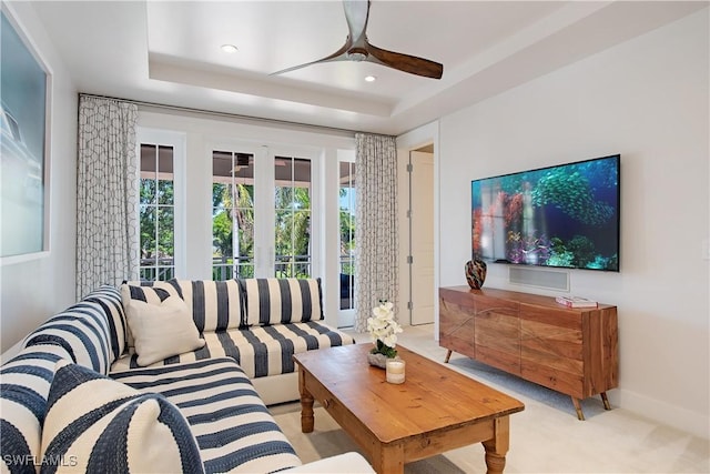 living area featuring recessed lighting, a tray ceiling, a ceiling fan, baseboards, and light colored carpet
