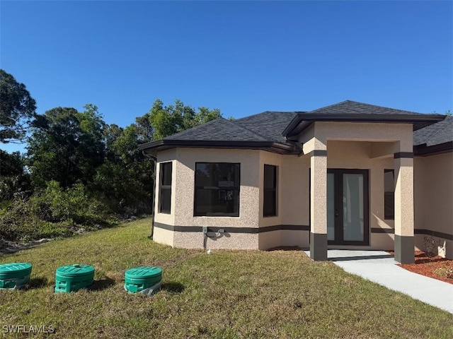 view of front of home with a front yard, roof with shingles, and stucco siding