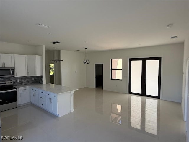 kitchen with tasteful backsplash, open floor plan, appliances with stainless steel finishes, a peninsula, and white cabinets