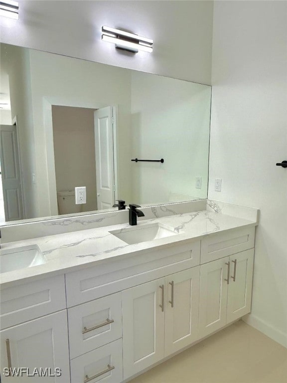 bathroom featuring double vanity, baseboards, and a sink