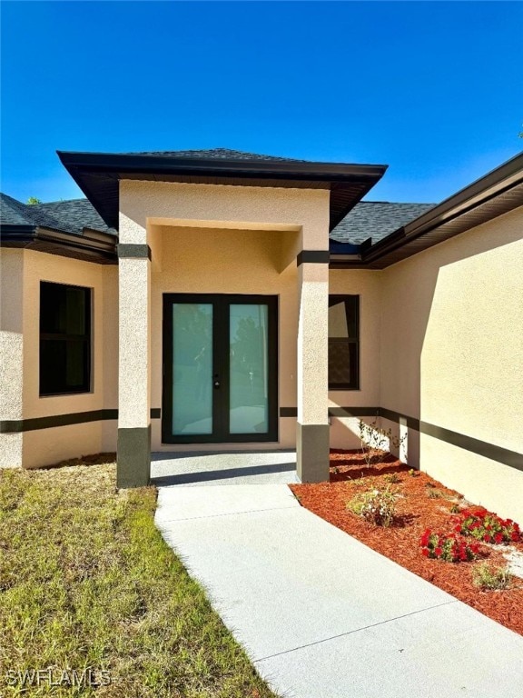 doorway to property featuring stucco siding, french doors, and a shingled roof
