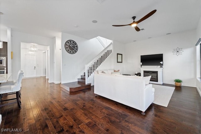 5135 Genoa St, Ave Maria, FL 34142 - living area featuring baseboards, stairway, ceiling fan with notable chandelier, dark wood-style floors, and a glass covered fireplace