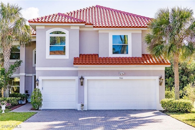 mediterranean / spanish home featuring a tiled roof, decorative driveway, an attached garage, and stucco siding