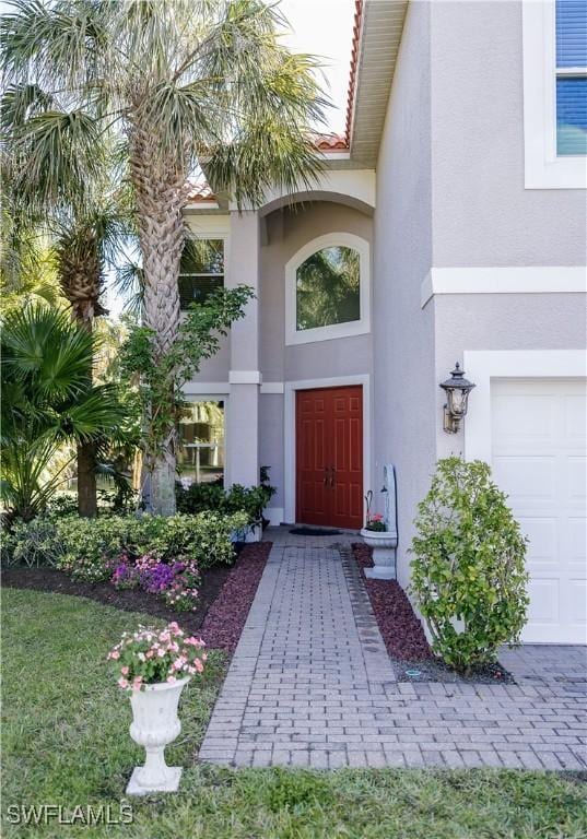 property entrance featuring a tiled roof, a garage, and stucco siding
