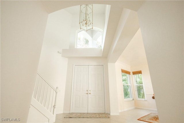 entrance foyer featuring a chandelier, tile patterned floors, baseboards, and a towering ceiling