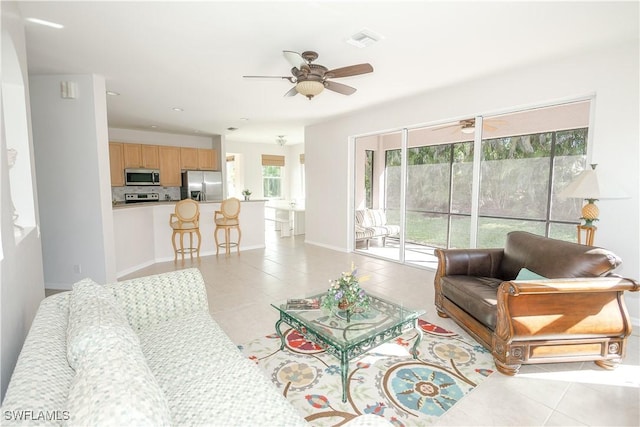 living area with light tile patterned flooring, visible vents, baseboards, and a ceiling fan