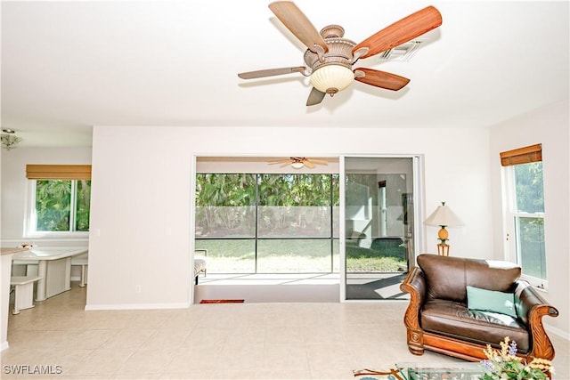 tiled living room with a wealth of natural light, visible vents, baseboards, and a ceiling fan