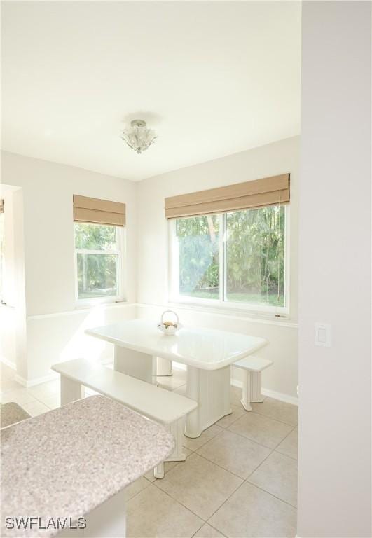 unfurnished dining area with light tile patterned floors, baseboards, and breakfast area