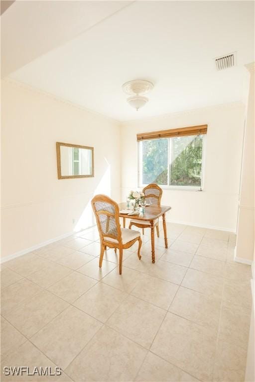 dining room featuring light tile patterned floors, visible vents, crown molding, and baseboards