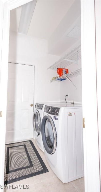 laundry area featuring laundry area, light tile patterned floors, and washing machine and clothes dryer