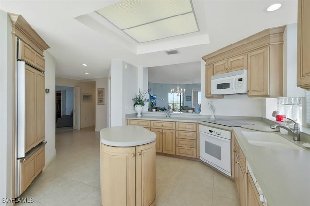 kitchen featuring light brown cabinetry, a sink, a kitchen island, white appliances, and light countertops