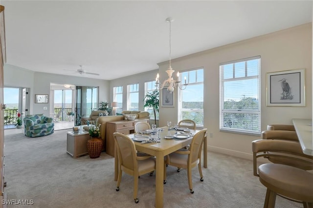 dining room featuring light carpet, a chandelier, and baseboards