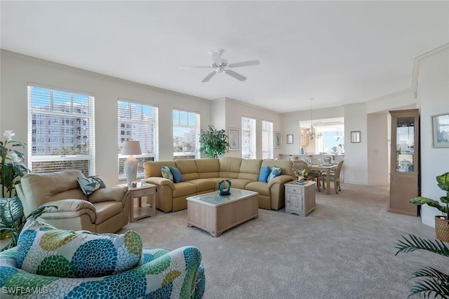 living room featuring light carpet and ceiling fan with notable chandelier
