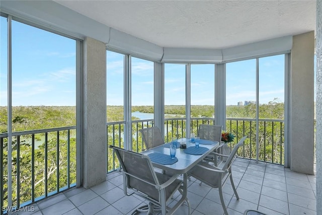 sunroom featuring a water view, a wealth of natural light, and a textured ceiling