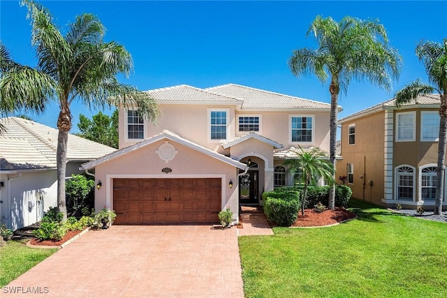view of front of property with driveway, a tile roof, a front yard, an attached garage, and stucco siding