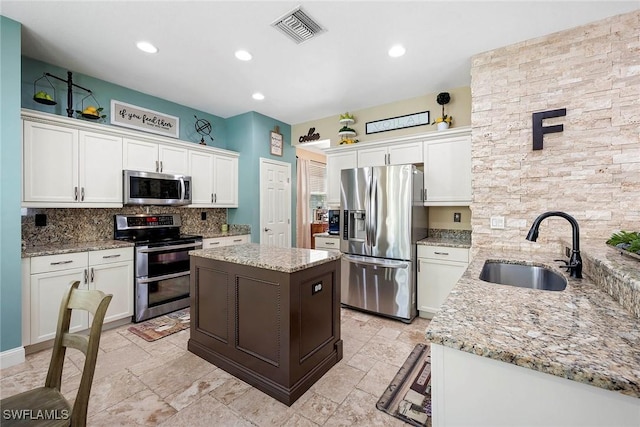 kitchen with tasteful backsplash, stainless steel appliances, white cabinets, a sink, and visible vents