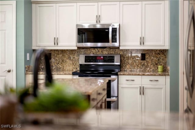 kitchen featuring dark stone counters, appliances with stainless steel finishes, decorative backsplash, and white cabinetry