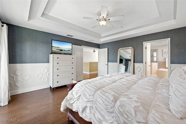 bedroom with wainscoting, wallpapered walls, dark wood-style floors, visible vents, and a tray ceiling