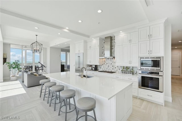 4971 Bonita Bay Blvd Unit Ph2503, Bonita Springs, FL 34134 - kitchen with stainless steel appliances, wall chimney range hood, white cabinets, backsplash, and a large island with sink