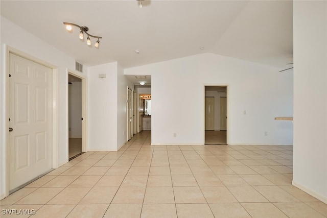 spare room with visible vents, light tile patterned floors, and lofted ceiling