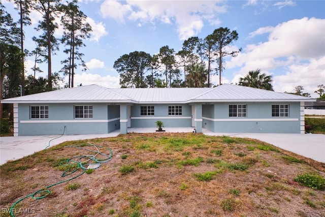 ranch-style house featuring metal roof and stucco siding