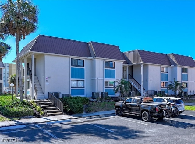 view of property with stairs and uncovered parking