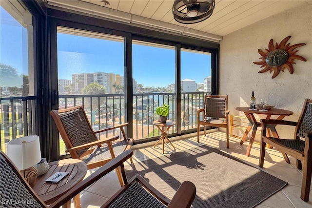 sunroom / solarium with a city view, wood ceiling, a wall of windows, and a textured wall