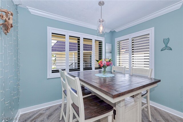 dining space with crown molding, wood finished floors, and baseboards