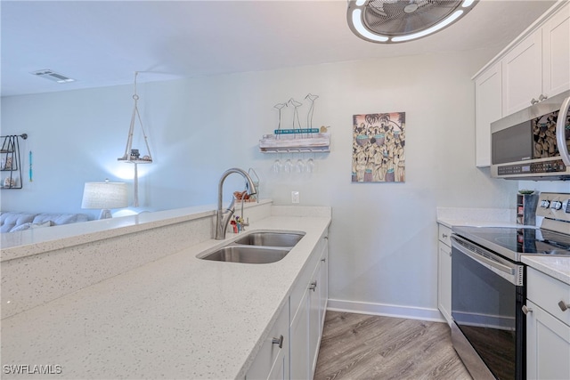 kitchen with visible vents, light wood-style floors, white cabinets, stainless steel appliances, and a sink