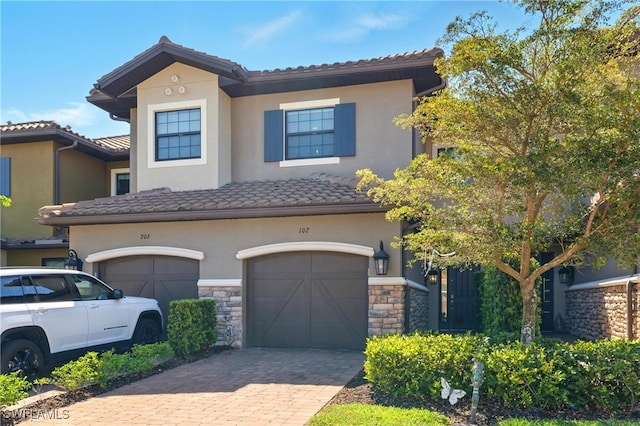 9654 Montelanico Loop Unit 102, Naples, FL 34119 - view of front of property featuring an attached garage, stucco siding, and stone siding