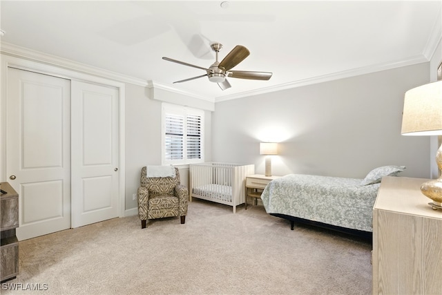 carpeted bedroom with crown molding, ceiling fan, and a closet