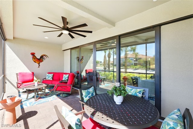 sunroom featuring beamed ceiling, outdoor lounge area, and a ceiling fan