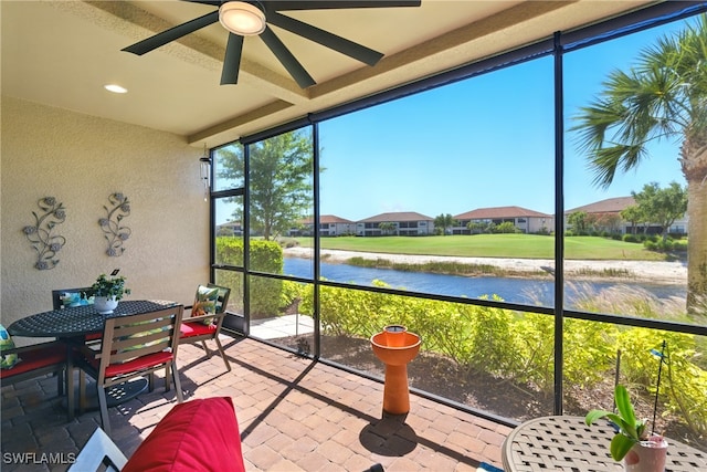 sunroom / solarium featuring a water view, a ceiling fan, and outdoor dining area