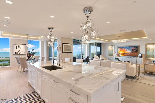 kitchen featuring a chandelier, a raised ceiling, and a sink