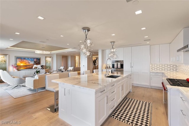 kitchen featuring a notable chandelier, a sink, open floor plan, appliances with stainless steel finishes, and light wood finished floors