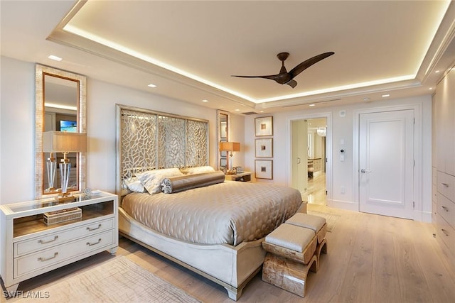 bedroom featuring recessed lighting, a tray ceiling, and light wood finished floors
